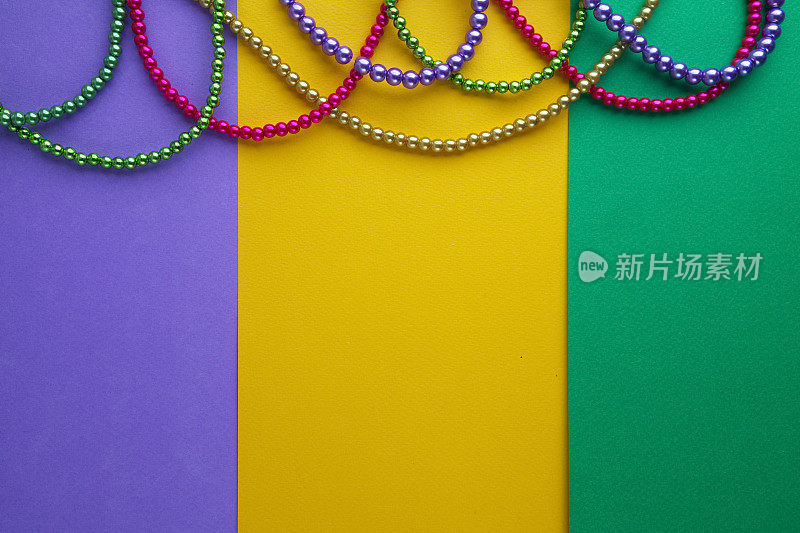 多色的Mardi Gras珠子在纸的背景。俯视图